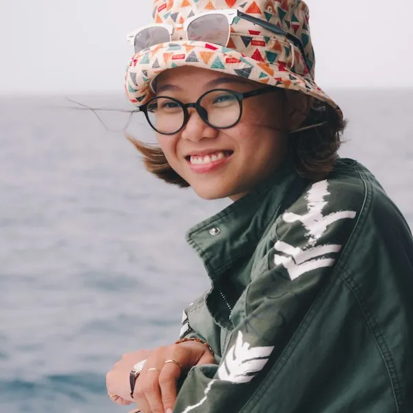 Smiling person wearing glasses and a hat