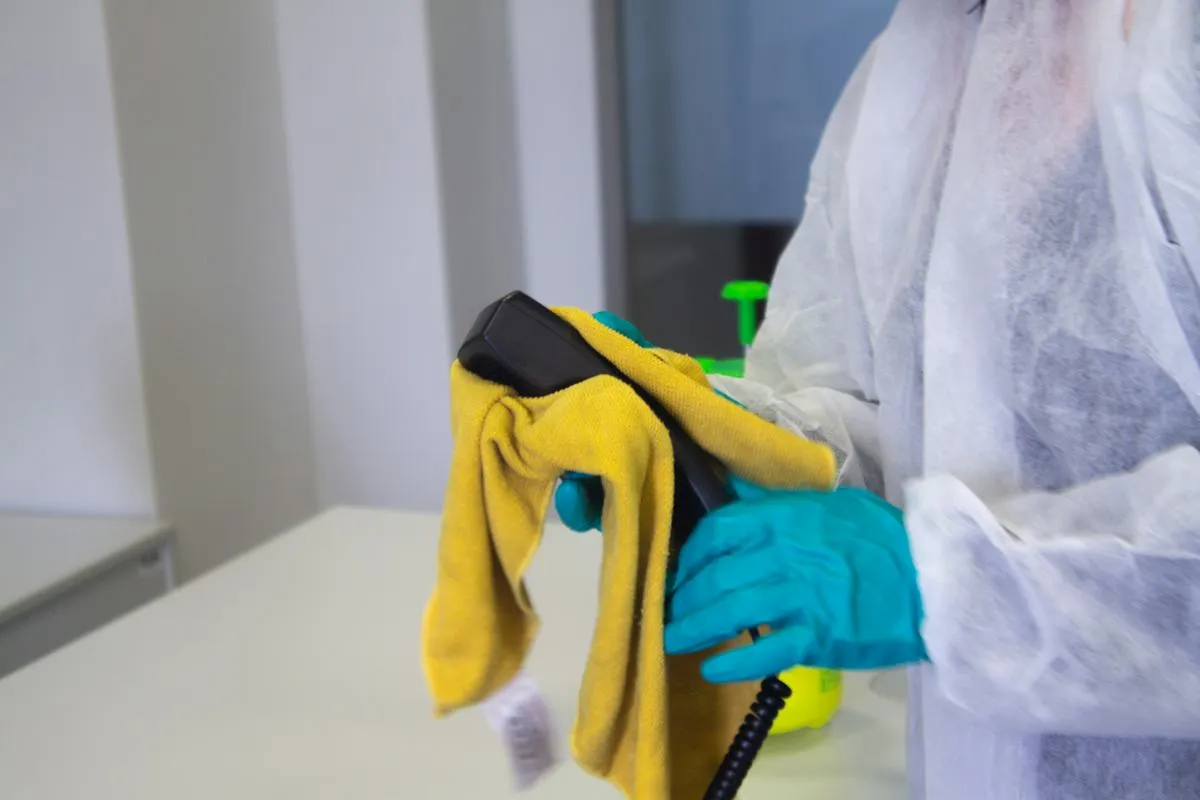 Gloved hand cleaning a fixture with a cloth