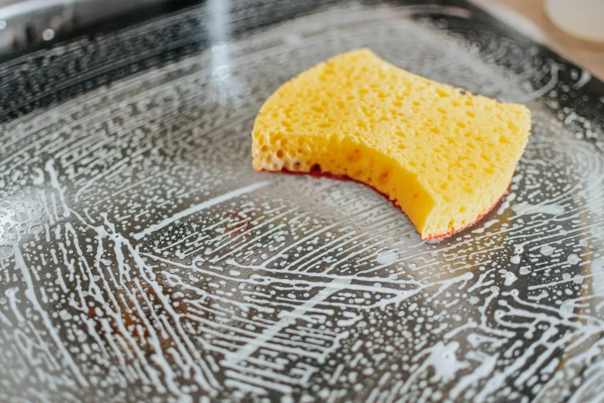 Yellow sponge wiping a wet glass surface