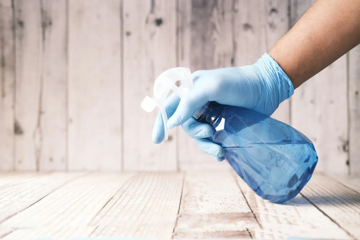 Gloved hand spraying a timber worktop