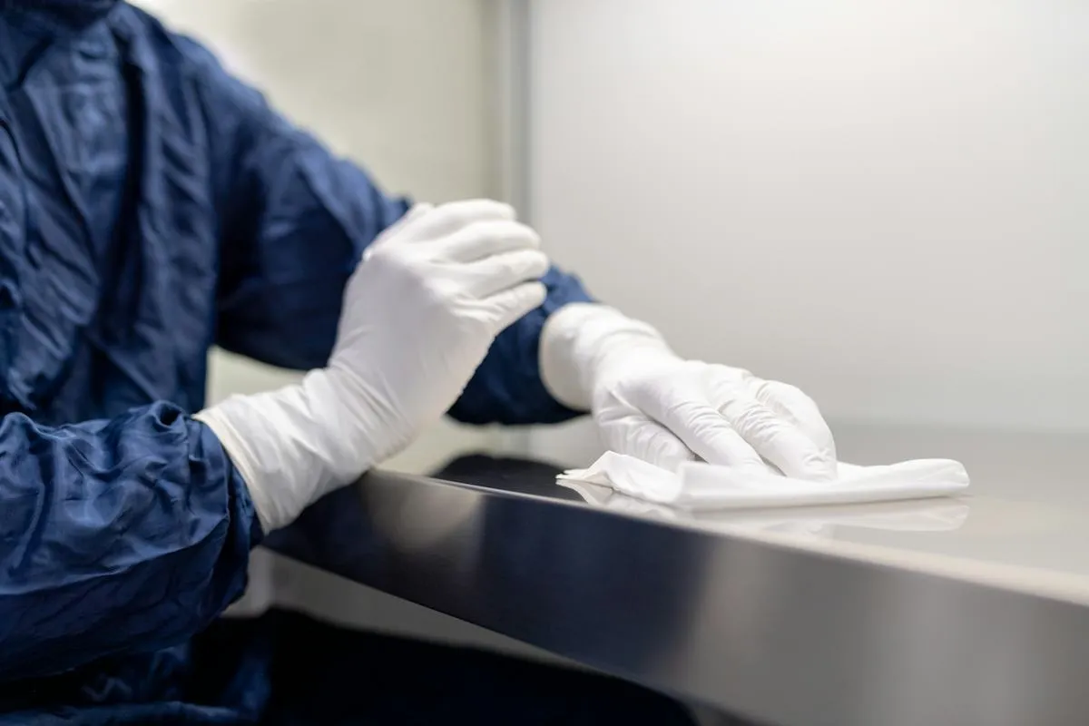 Cleaner wearing gloves wiping a kitchen surface